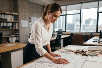 Étudiante en architecture d'intérieur en alternance consultant des plans sur une table de travail dans un studio de design professionnel